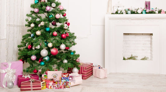 A pile of christmas presents under a christmas tree in a white tone livingroom.