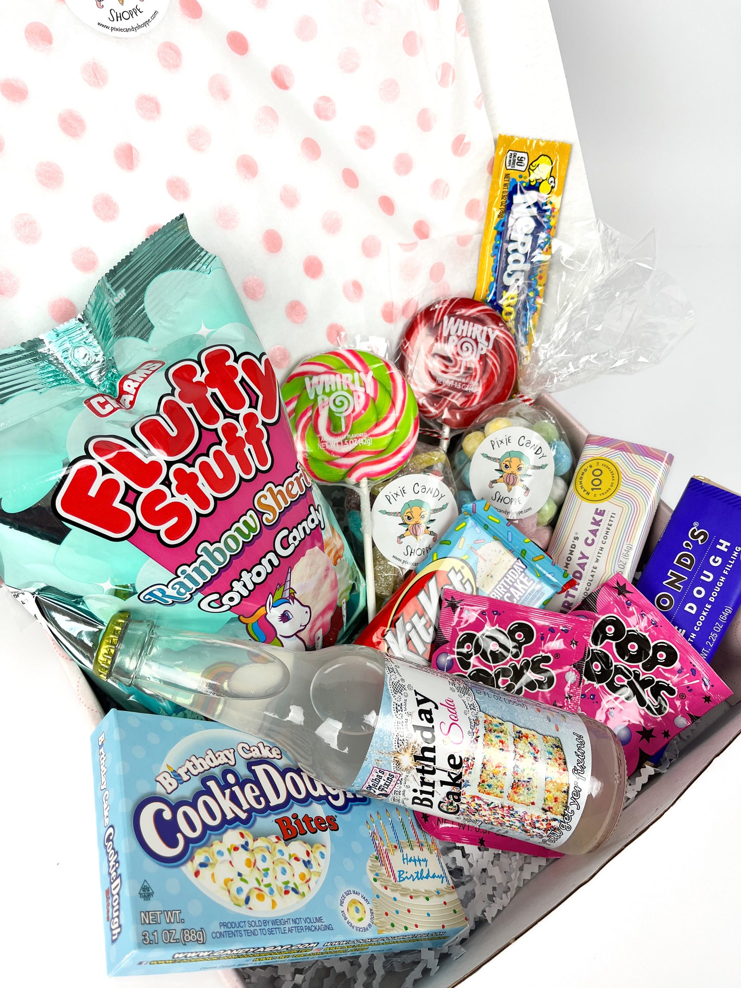 An assortment of birthday themed candy and treats inside a branded shipping box.